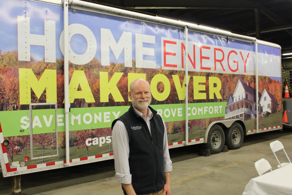 Man in vest smiling before a trailer that reads Home Energy Makeover