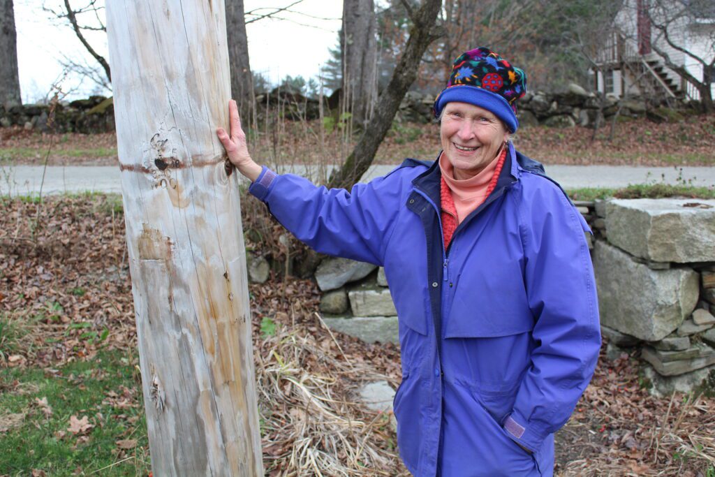 Woman in jacket leans against utility pole